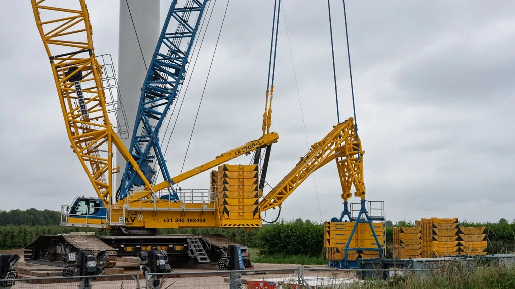 A 60-ton crawler crane erecting a steel bridge girder on a winter morning